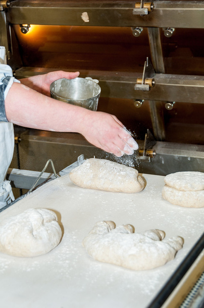 Baker preparing bread before  baking - Foto, afbeelding