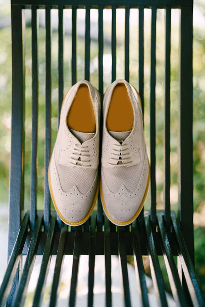 Γκρι mens oxford παπούτσια σε μια ξύλινη καρέκλα στον κήπο. - Φωτογραφία, εικόνα