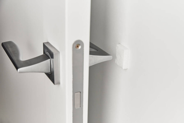 Tirador de puerta plateado en puerta blanca. Accesorios para muebles, elemento interior - Foto, Imagen