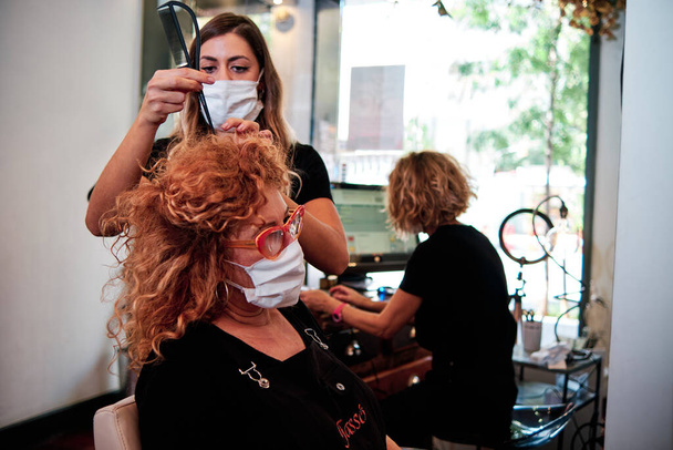 mujer en peluquería con máscaras protectoras - Foto, imagen