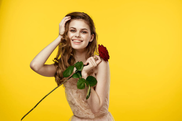 Romantic woman in evening dress with red rose on yellow background cropped view portrait - Фото, изображение