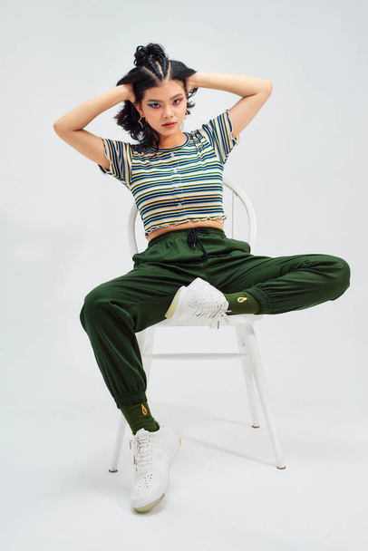 teenage girl playing on a chair. On a gray background - Photo, Image