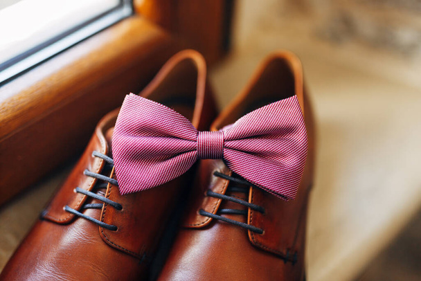 Close-up of a pink bow tie on brown mens shoes. - Foto, imagen