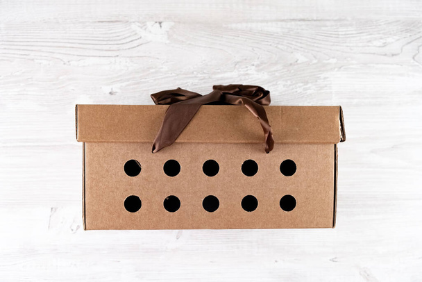 подарункова картонна коробка з коричневим бантом на білому дерев'яному столі, концепція служби доставки
 - Фото, зображення