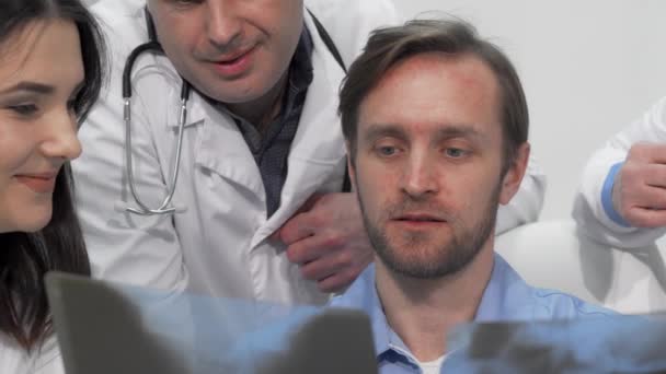 Plan recadré glissant de l'équipe médicale examinant la radiographie ou l'IRM ensemble - Séquence, vidéo