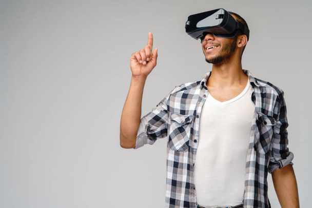 Young African-American young man wearing vr virtual reality headset over light grey background - Foto, afbeelding