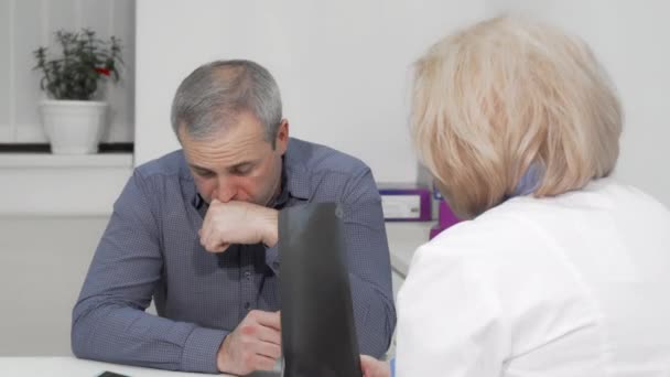 Dojrzały mężczyzna kaszel na wizytę lekarską z jego lekarzem - Materiał filmowy, wideo