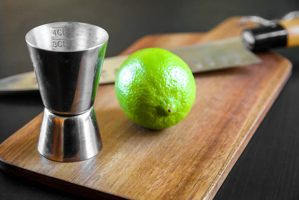 Cocktail dispenser, lime and traditional Japanese gyuto chief knife on a cutting board. - Fotografie, Obrázek