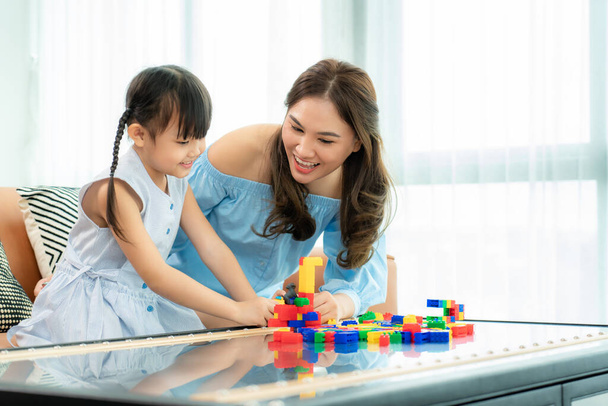Azjatycka rodzina spędza czas w pokoju zabaw z matką i córką z zabawkami na tle pokoju zbudować z plastikowych bloków w salonie w domu - Zdjęcie, obraz