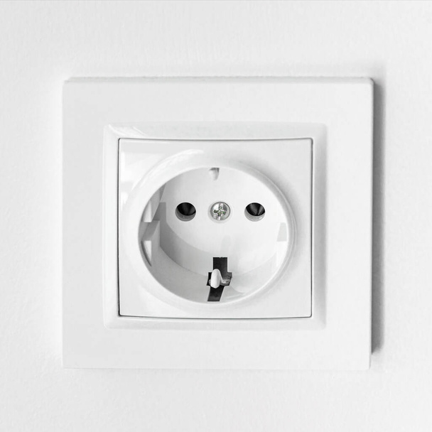Het witte plastic stopcontact wordt in een witte wand gemonteerd - Foto, afbeelding