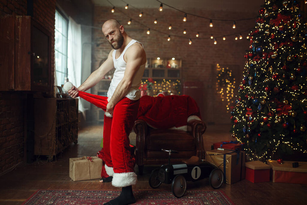 Böser, schamloser Weihnachtsmann mit rotem Hut, fieser Party, Humor. Ungesunder Lebensstil, bärtiger Mann im Urlaubskostüm, Silvester und Alkoholismus - Foto, Bild