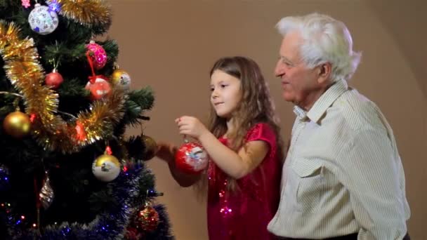Klein meisje met grootvader die thuis kerstboom versiert. Kerstmis, Nieuwjaar interieur. generatie en mensen concept - Video