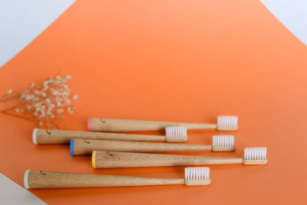 Set of wooden bamboo toothbrushes on orange background with copy space. - Photo, Image