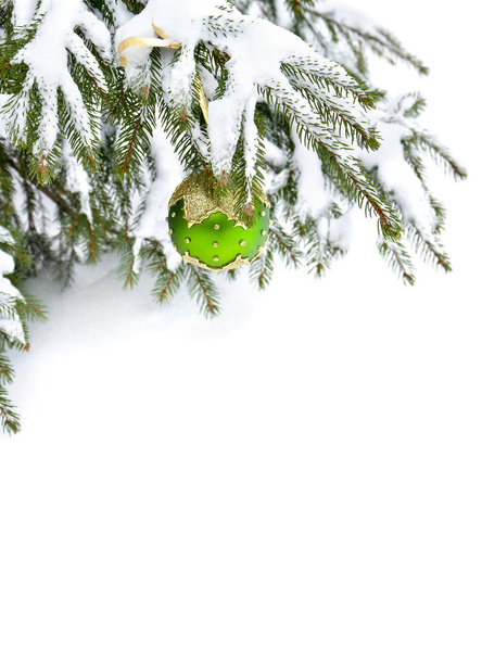Sprig van kerstboom met hangende bal in sneeuw in de winter dennenbos tijdens sneeuwval met ruimte voor tekst - Foto, afbeelding