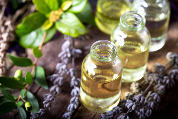 Ätherisches Lavendelöl in kleinen Fläschchen auf Holzgrund. Aromatherapie-Werkzeuge, Flaschen mit Öl und Lavendelblüten. - Foto, Bild