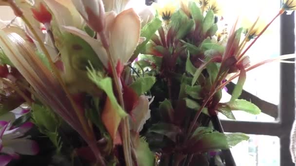 Színes mesterséges virágok a teraszon kert és buja zöld növények ott - Felvétel, videó