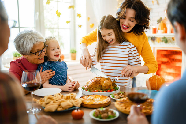 Happy Thanksgiving Day! Autumn feast. Family sitting at the table and celebrating holiday. Grandparents, mother, father and children. Traditional dinner. - Фото, зображення