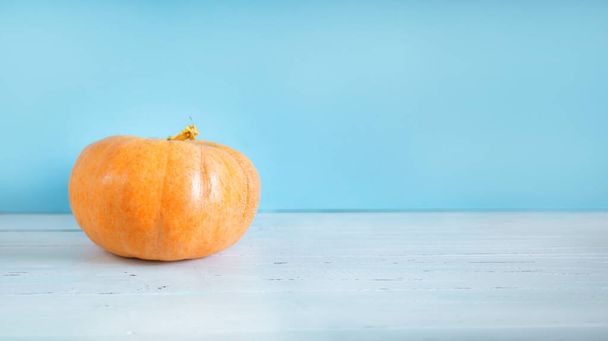 Big pumpkin on a white table, preparation for Halloween - Foto, afbeelding
