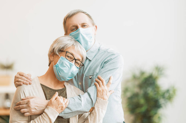 Senior couple wearing facemasks during coronavirus and flu outbreak. Virus and illness protection, home quarantine. COVID-2019. Taking on or taking off masks. - Foto, Bild