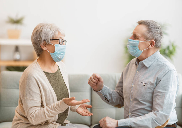 Senior couple wearing facemasks during coronavirus and flu outbreak. Virus and illness protection, home quarantine. COVID-2019. Taking on or taking off masks. - Foto, imagen