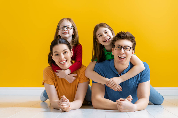 Happy loving family. Mother, father and children daughters on yellow background.  - Фото, зображення