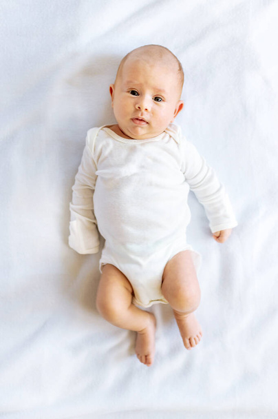 Un neonato giace su un letto bianco. Concentrazione selettiva. Persone. - Foto, immagini