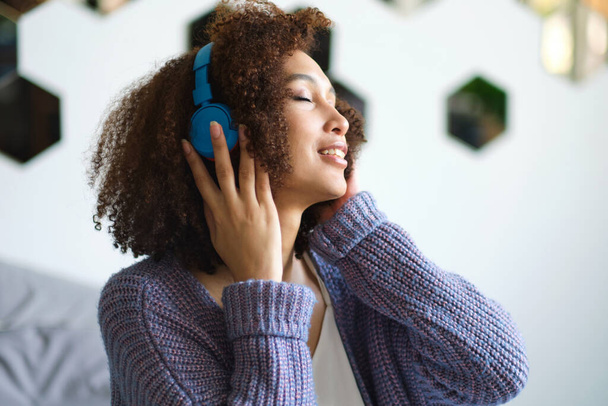 Adorable mujer americana en cantar y divertirse mientras escucha música usando auriculares inalámbricos - Foto, Imagen