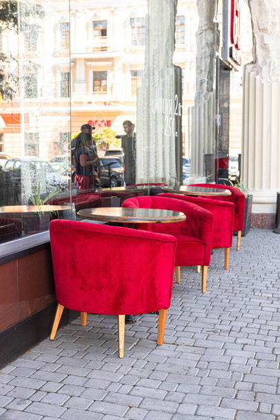 Pouliční kavárna, stylové minimalistické prázdné stoly s krásnými červenými sametovými židlemi ve venkovní restauraci. Svislá orientace fotografie - Fotografie, Obrázek