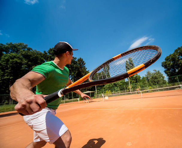 Young athletic man playing tennis on the court. - Фото, зображення