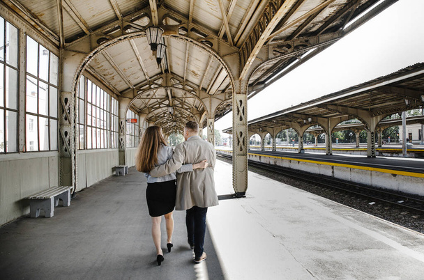 in love couple - the guy in vintage coat girl in a gray leather jacket - a walk on the Vitebsk railway station in Saint  Petersburg, happy and hugging - Foto, Imagem