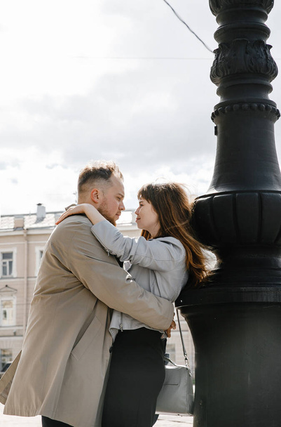 in love couple - the guy in vintage coat girl in a gray leather jacket - a walk on the Vitebsk railway station in Saint  Petersburg, happy and hugging - Фото, изображение