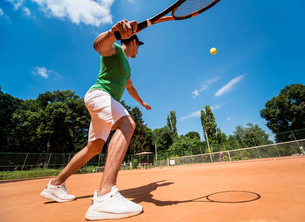 Young athletic man playing tennis on the court. - Photo, image