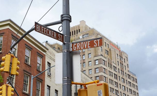Street signs in New York City for Bleecker Street and Grove Street on a traffic light pole. Apartment buildings beyond. - Fotoğraf, Görsel