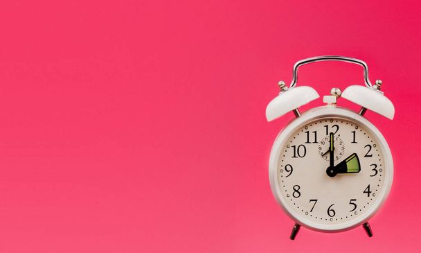 Antike Uhr auf rosa Pop-Art-Hintergrund, die die Verzögerung aufgrund der Winterzeitumstellung markiert. Eine Stunde Verspätung, eine Stunde Verspätung, eine Stunde zurück - Foto, Bild
