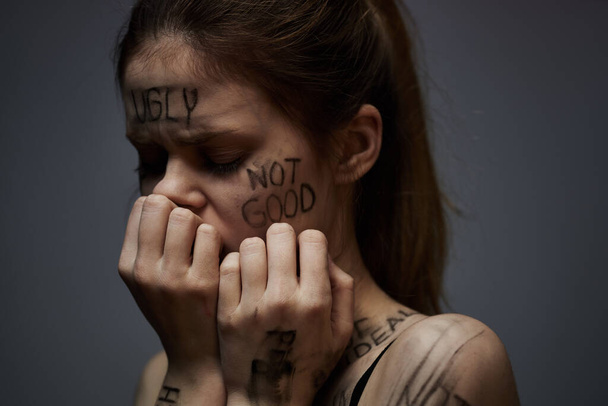 γυναίκα με προσβλητικές επιγραφές στο σώμα της αγγίζοντας τον εαυτό της με τα χέρια άγχος απογοήτευση μίσος - Φωτογραφία, εικόνα