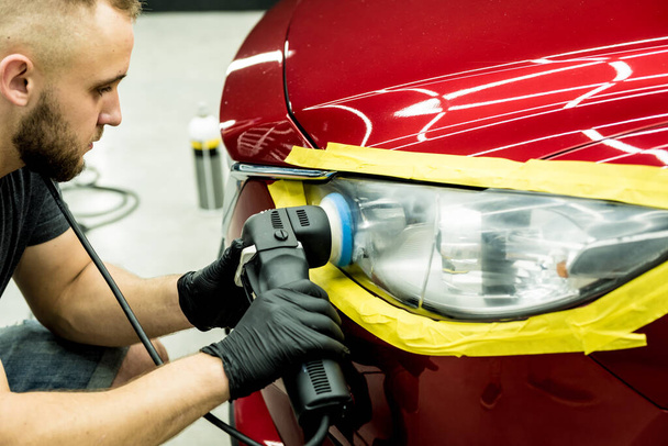 Car service worker polishes a car details with orbital polisher. - Photo, Image
