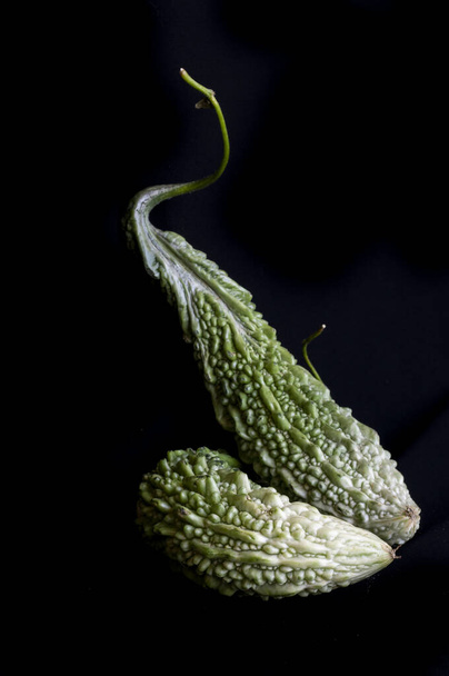 Verduras de cabaça amarga em um fundo preto liso. Foto de alta qualidade - Foto, Imagem