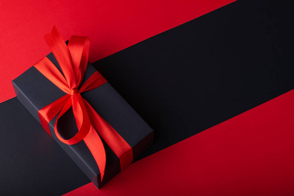 Top view of black boxes with red ribbon on black background and red background. Black Friday and Boxing Day. - Foto, imagen
