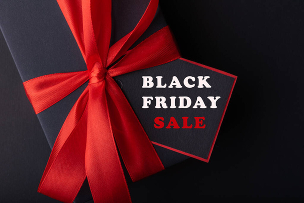 Top view of black boxes with red ribbon on black background and red background. Black Friday and Boxing Day. - 写真・画像
