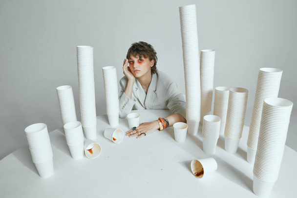 Tired girl with lots of paper cups for coffee. Hard morning, chronic lack of sleep and caffeine addiction concept - Fotó, kép