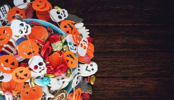 Halloween Jack o Laterne Süßigkeitenschale mit Süßigkeiten und Halloween-Plätzchen Trick or Treat auf schwarzem Holzhintergrund - Foto, Bild