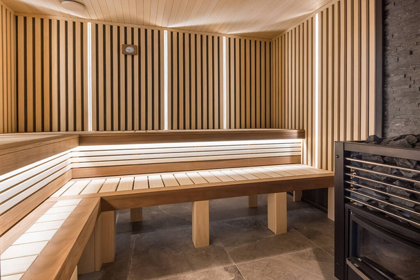 Modern wooden sauna interior with elegant lighting and electric heater - Фото, изображение