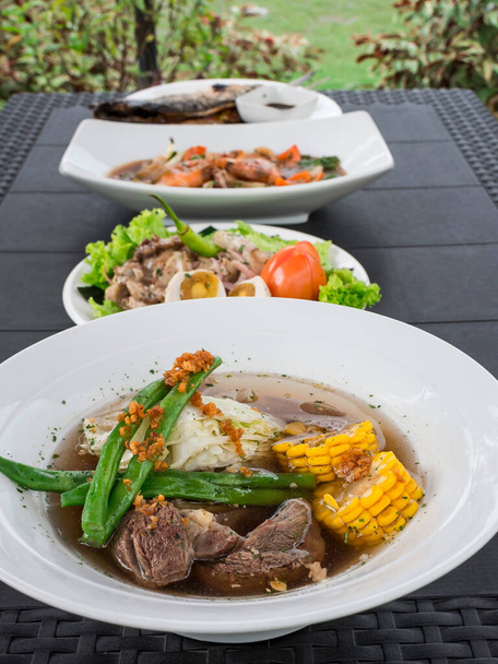 Van onder naar boven: rundvlees Bulalo, Dinakdakan, Chop Suey, en gevulde Bangus. Voorbeeld van Filippijnse keuken. Buiten tuin instelling. - Foto, afbeelding