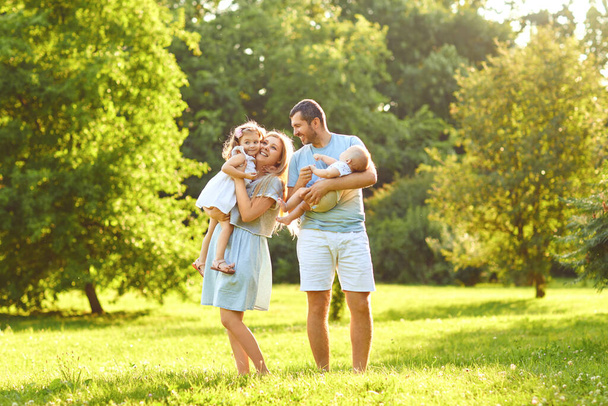 Family with baby stands on grass in the park - Photo, image