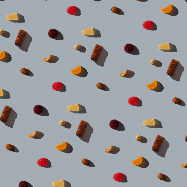 Bezproblémové pozadí s marmeládou, různými ořechy a čokoládou na špinavě modré textuře. Tvrdý stín. Pohled shora, byt ležel - Fotografie, Obrázek