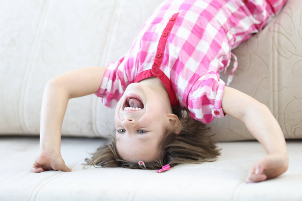 Happy girl stand on her head on sofa. - Photo, Image