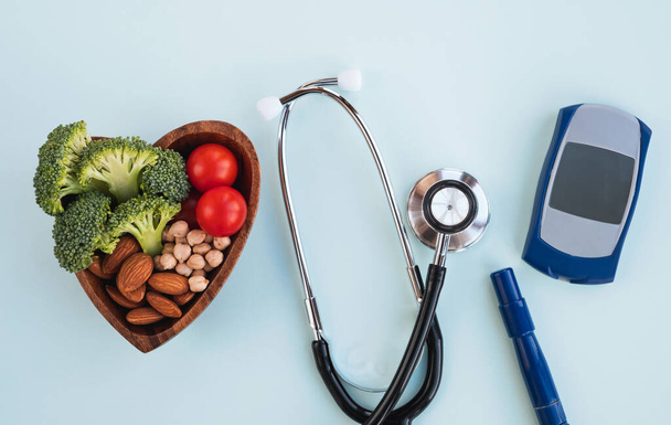 Diabetes concept. Healthy food, digital glucometer, lancet pen and medical stethoscope on light blue background. Top view - Fotó, kép