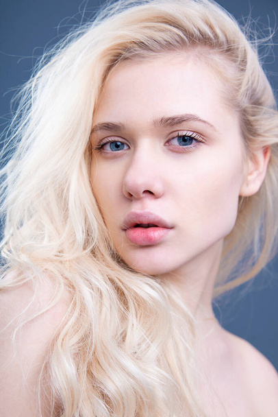 Schönheit Nahaufnahme Porträt der jungen schönen blonden jungen Frau Gesicht natürliche Make-up, Blick in die Kamera, grauer Hintergrund. - Foto, Bild