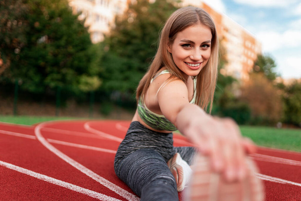Positive sports girl doing stretching before running - Zdjęcie, obraz