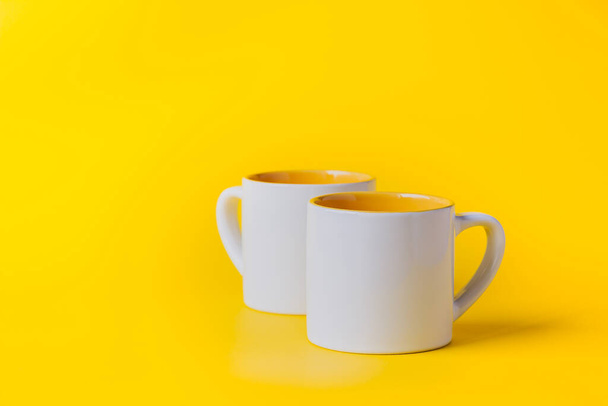 Empty coffee or tea white cup with yellow on yellow background. Copy space. - Photo, Image